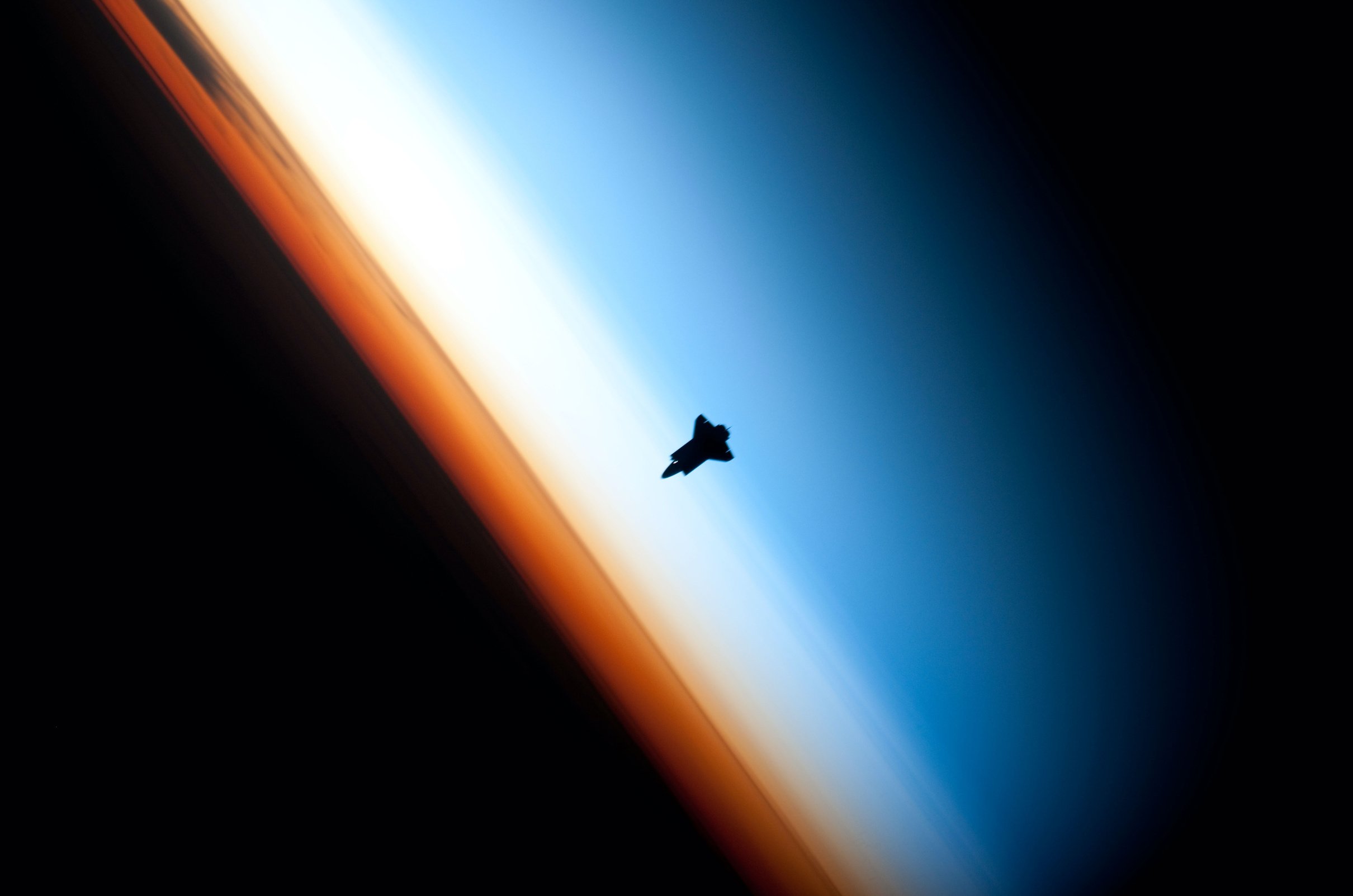 Space Shuttle Endeavour's silhouette against the Earth's colorful horizon